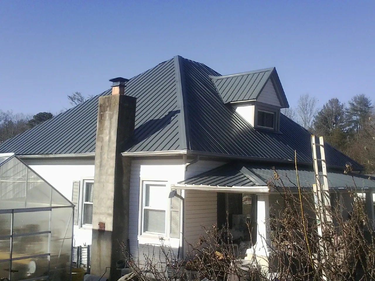 Dark blue standing seam metal roof on a white farmhouse with dormer — Slate & Tile Roof Repair by Roofing Brothers in Decatur