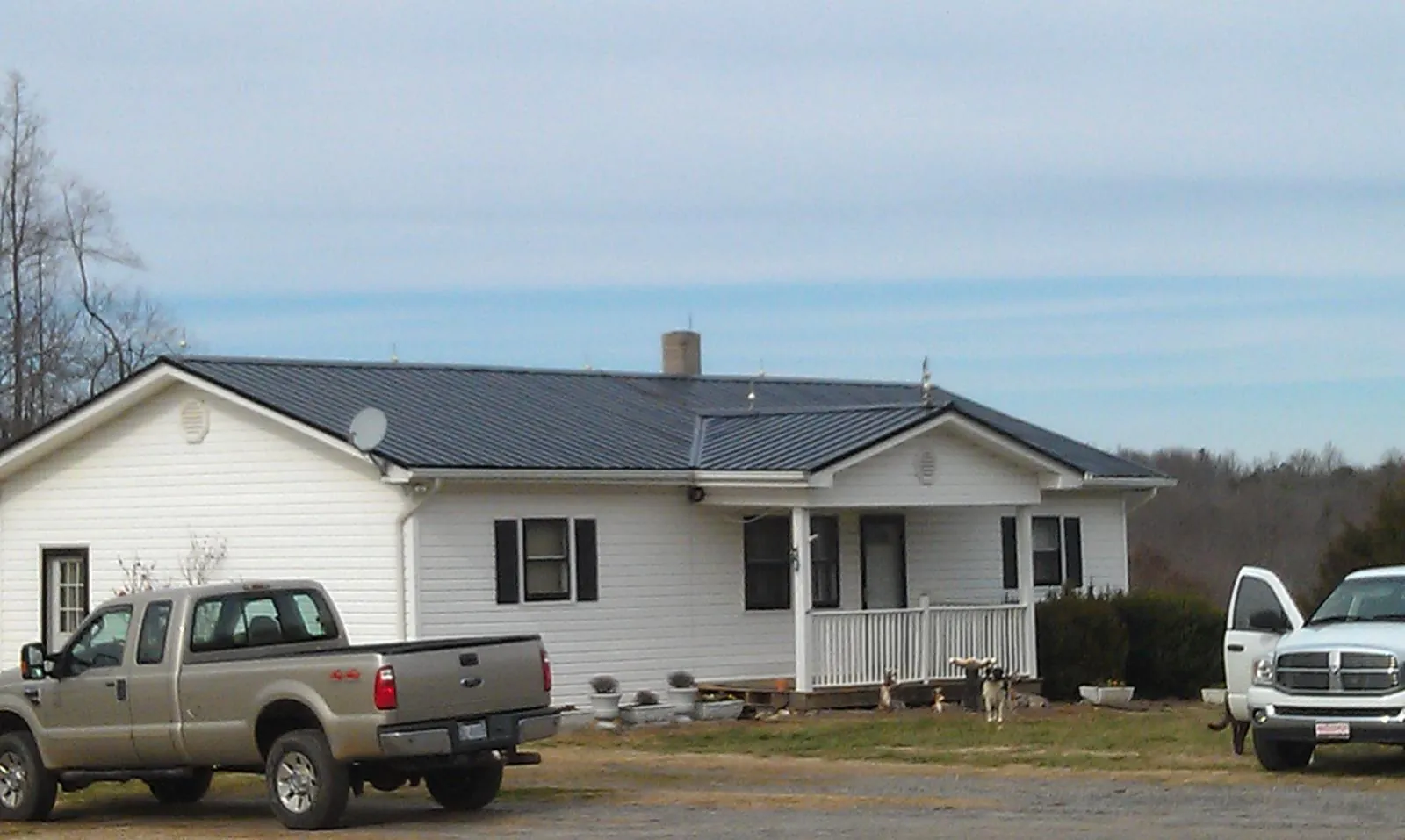Finished dark metal roof on a white ranch home with work trucks parked in Decatur